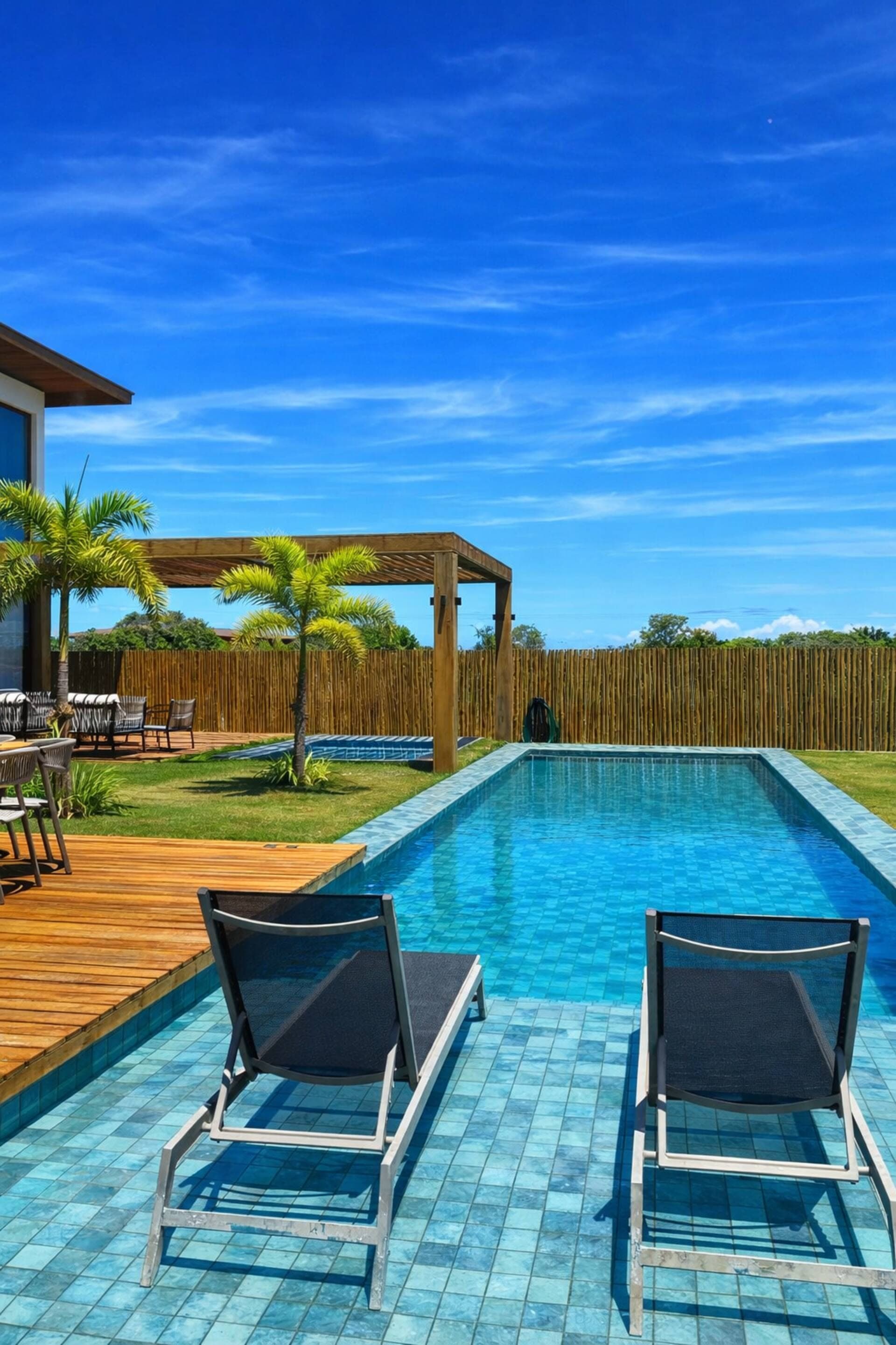 Duas espreguiçadeiras dentro da piscina, em dia de céu azul