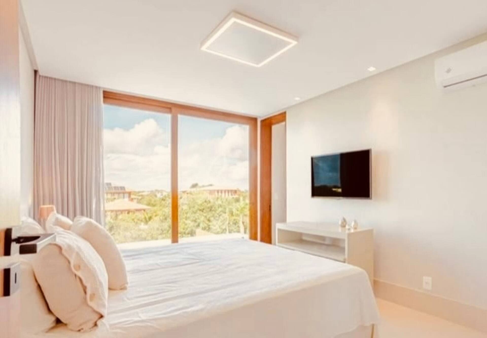 Quarto com cama de casal, TV na parede, ar-condicionado e porta de vidro para o exterior